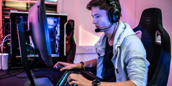 a person sitting in front of a computer playing video games like Kingdom Come: Deliverance 2 Image source: https://unsplash.com/photos/a-man-wearing-a-headset-and-using-a-computer-oPrXf-0Nf9Q