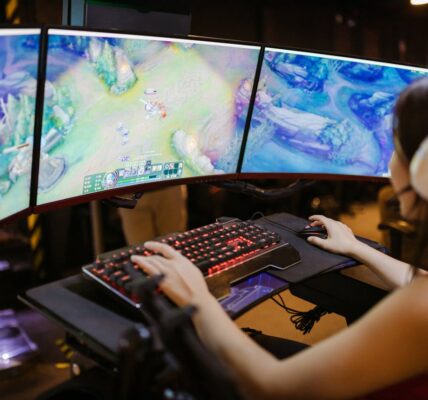 a woman playing League of Legends on three-monitor PC setup