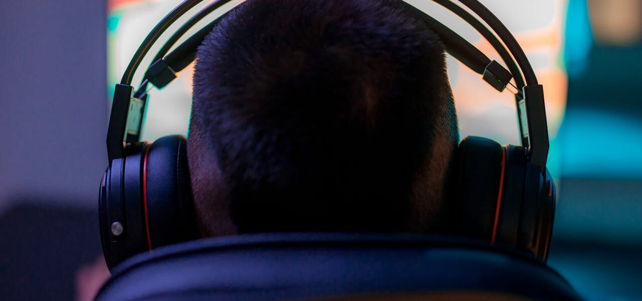 a back view of a person wearing headphones in front of a PC playing Avowed