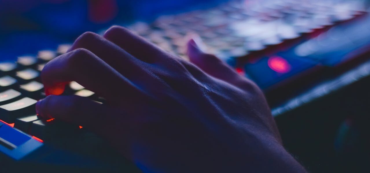 a persons hand on a mechanical keyboard with RGB lighting playing Indiana Jones and The Great Circle