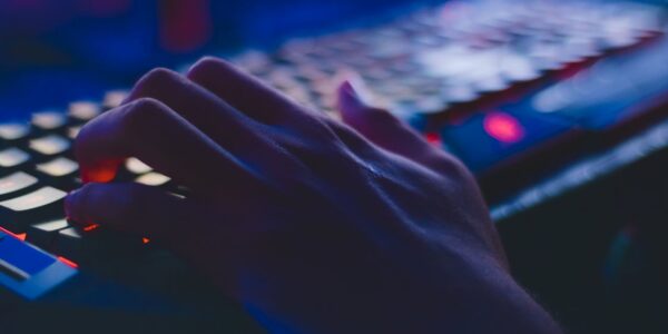 a persons hand on a mechanical keyboard with RGB lighting playing Indiana Jones and The Great Circle