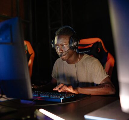 a person sitting in a dark room in front of their PC playing Hell Let Loose