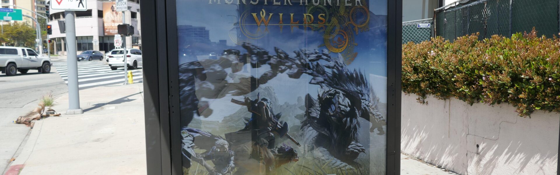 a billboard on the street that promotes Monster Hunter Wilds for Playstation 5