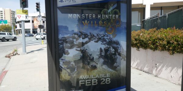 a billboard on the street that promotes Monster Hunter Wilds for Playstation 5