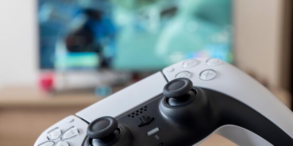 a person holding a white PS 5 controller with a video game on screen to represent the hype for Lost Soul Aside coming in August