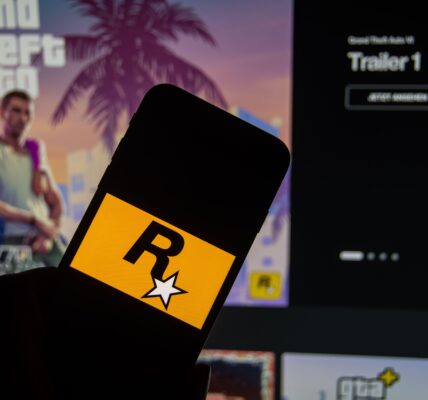 a person holding a phone with the Rockstar logo with GTA VI trailer in the background on a monitor