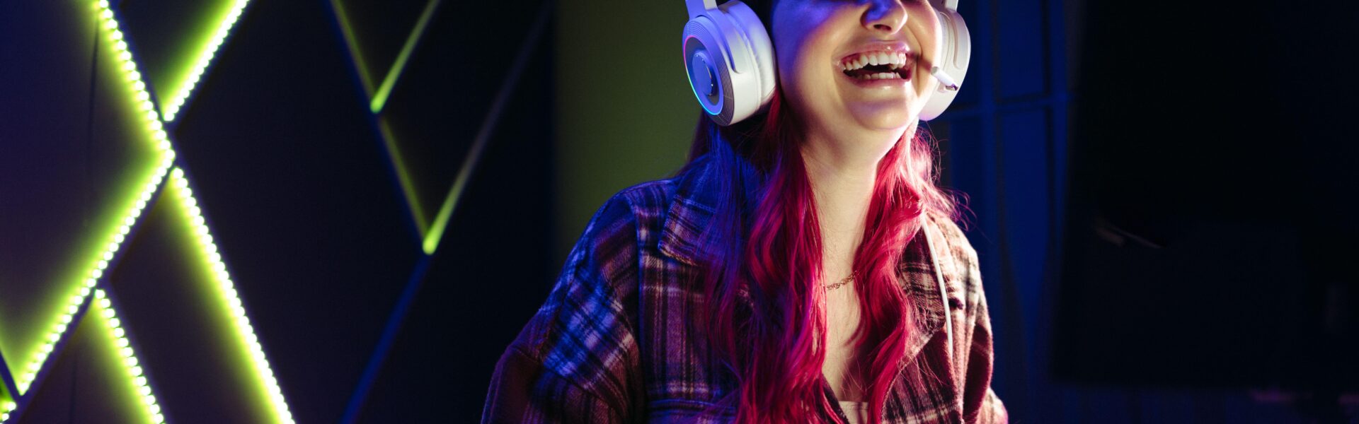 a woman laughing while playing Clair Obscur: Expedition 33 on her PC inside an LED lit room