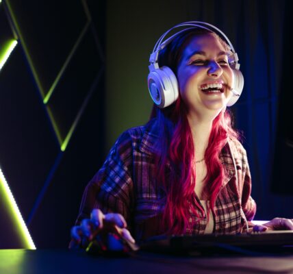 a woman laughing while playing Clair Obscur: Expedition 33 on her PC inside an LED lit room