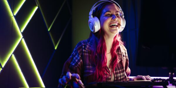 a woman laughing while playing Clair Obscur: Expedition 33 on her PC inside an LED lit room