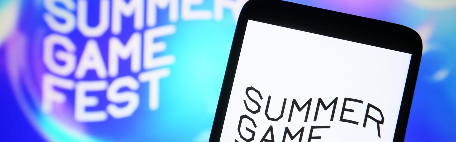 a Summer Game Fest logo on a phone and the wall to represent the day and place Mafia: The Old Country got announced