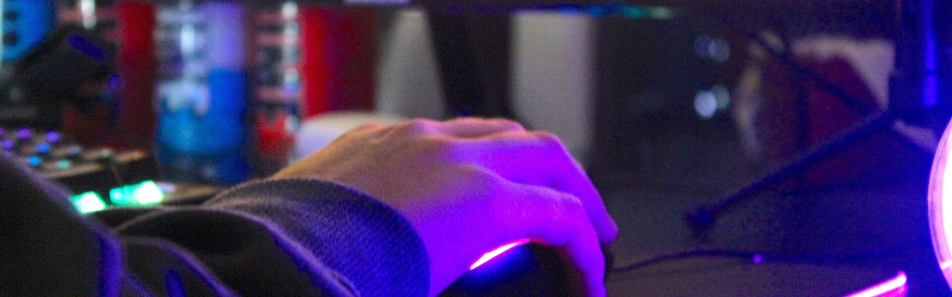 a man playing Project Zomboid on his PC with purple lights lighting his mouse pad