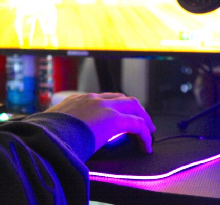 a man playing Project Zomboid on his PC with purple lights lighting his mouse pad