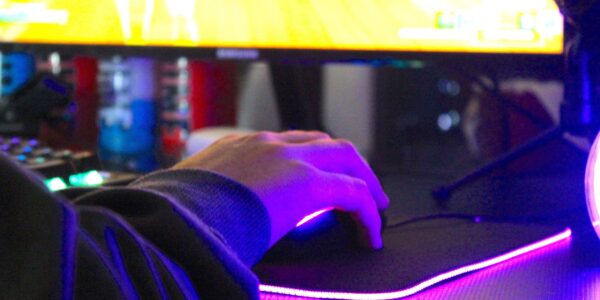 a man playing Project Zomboid on his PC with purple lights lighting his mouse pad