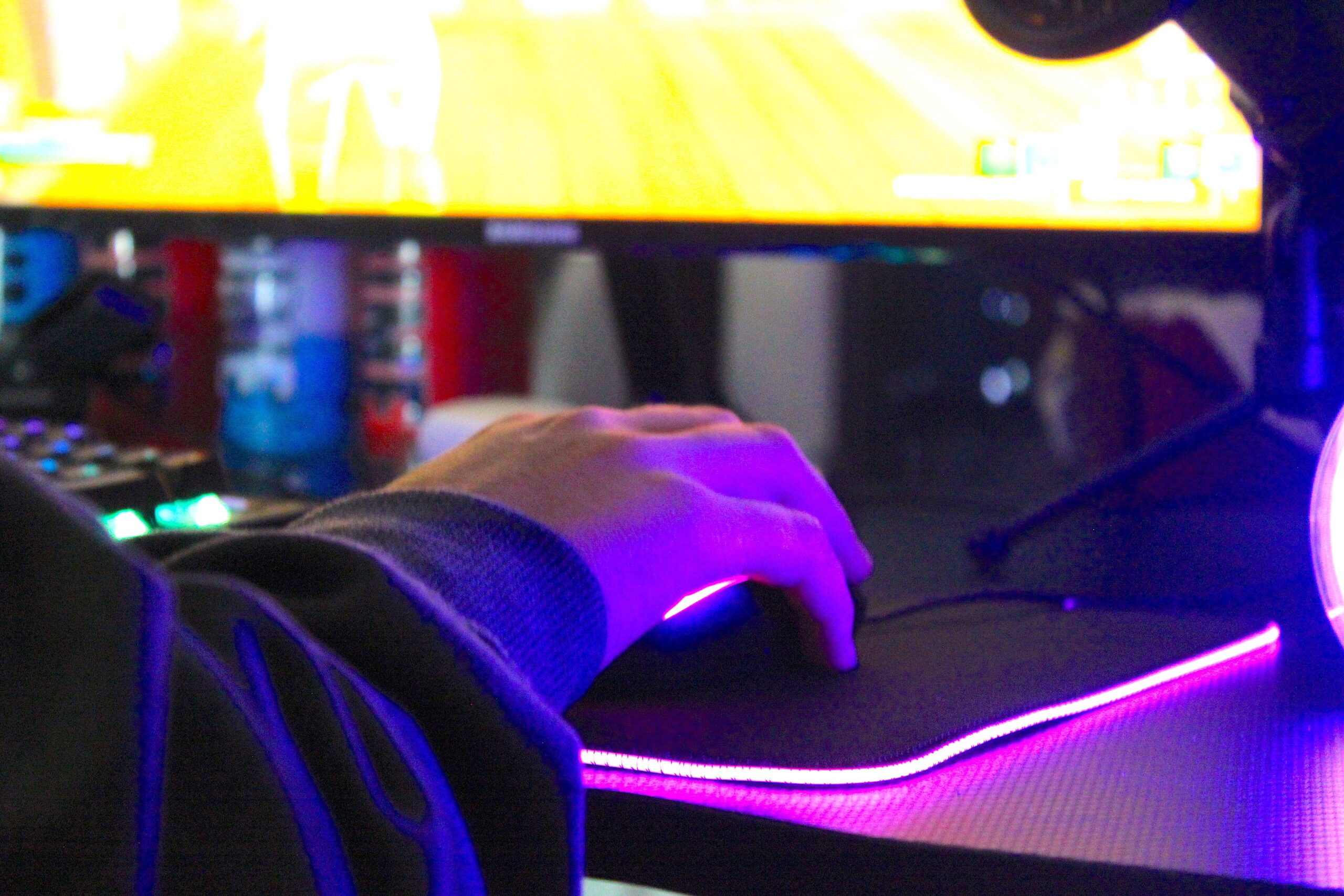 a man playing Project Zomboid on his PC with purple lights lighting his mouse pad