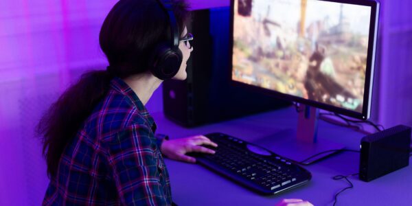 a woman playing Rust on her PC in a purple lit room