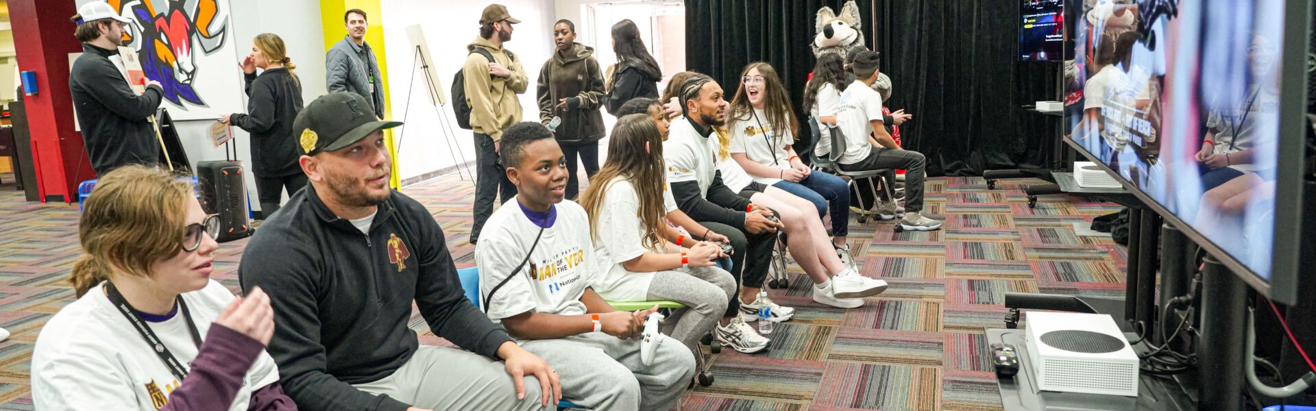 children playing the new College Football 26 with adults in a room
