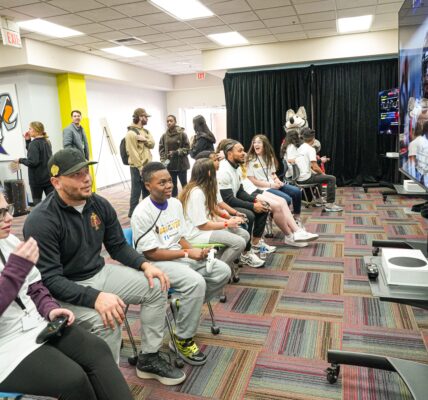 children playing the new College Football 26 with adults in a room