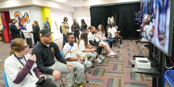 children playing the new College Football 26 with adults in a room