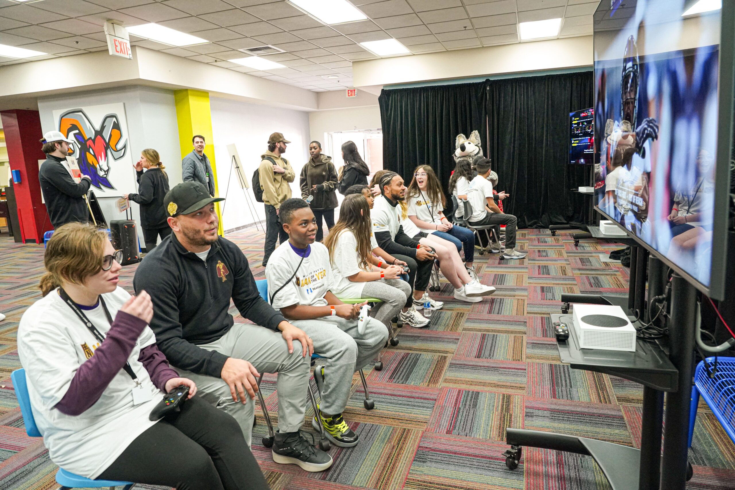 children playing the new College Football 26 with adults in a room
