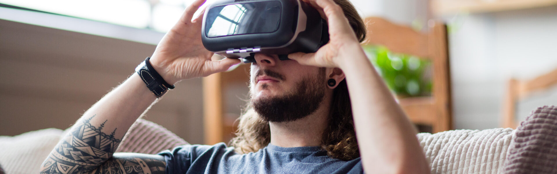 a man sitting on a couch in his home playing Chrono Weavers on his VR