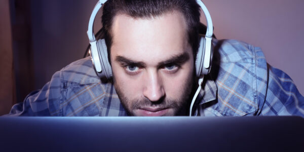 a man leaning into the monitor with a headset on while playing the intense roguelite The King is Watching